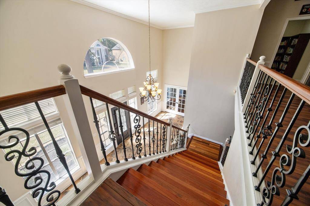 Featuring wrought-iron balusters and a stunning chandelier, this staircase offers a dramatic view of the soaring two-story foyer from the game room.