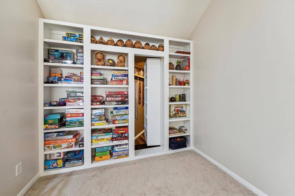 Concealed behind this bookshelf is a hidden passageway leading to the sixth bedroom with a full bathroom, currently utilized as a tropical themed entertainment space with a bar area. This space would make a great mother in law suite as it is private and tucked away.