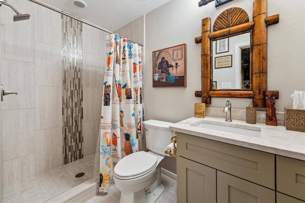 This charming on suite bathroom to the private sixth bedroom features a walk-in shower with modern tile accents and a sleek vanity with marble countertop