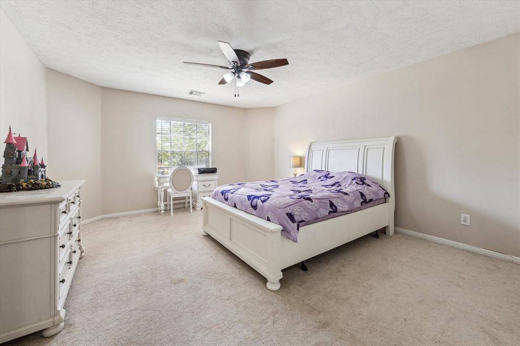 One of the five large upstairs bedrooms on the left of the home overlooking the front yard and features carpeting, a large closet, and ceiling fan.