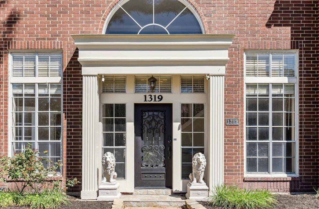 A closer look at the home shows a grand entryway with stately columns and side light windows around the iron door. Note: The lion statues do not stay with the home.