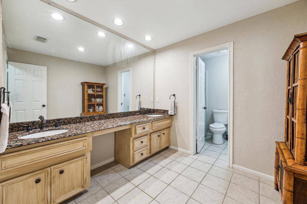 Conveniently shared by two upstairs bedrooms, this large bathroom features dual sinks with granite countertops, a built-in vanity space, large wall mirror and ample storage. The separate room features the toilet and the tub/shower combo providing added privacy, while recessed lighting and neutral tile flooring enhance the bright and airy feel.