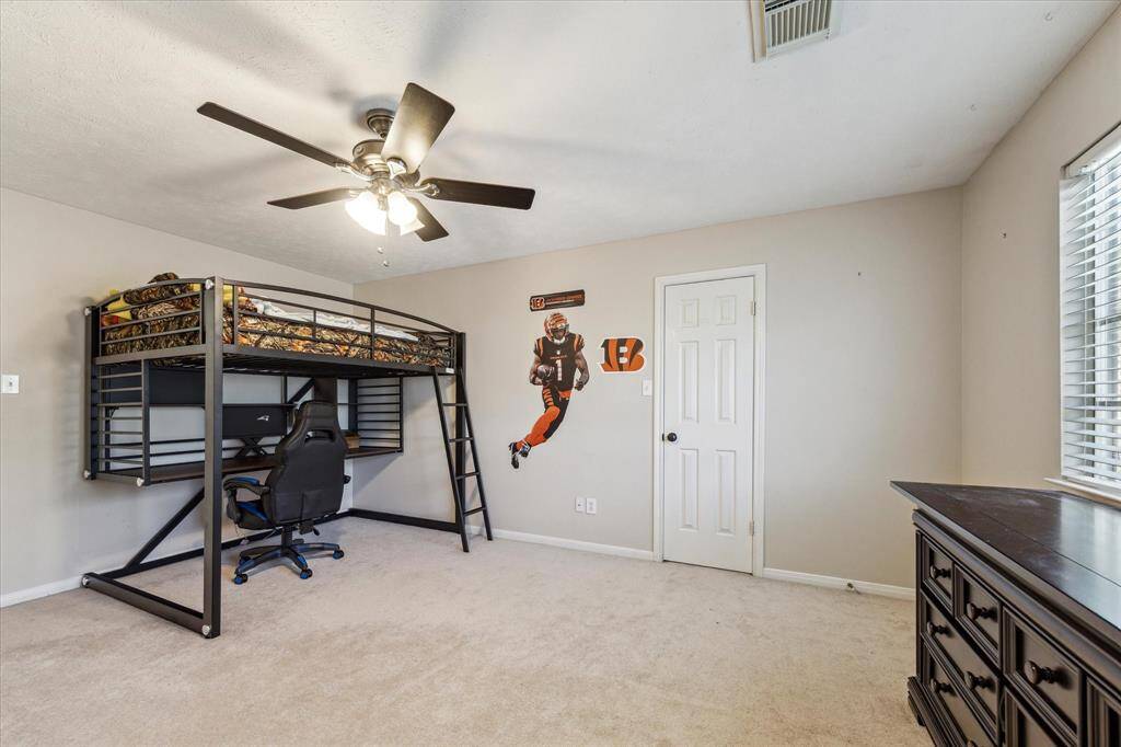 Bedroom two of five large upstairs bedrooms on the left of the home overlooking the back yard and features carpeting, a large closet, and ceiling fan.