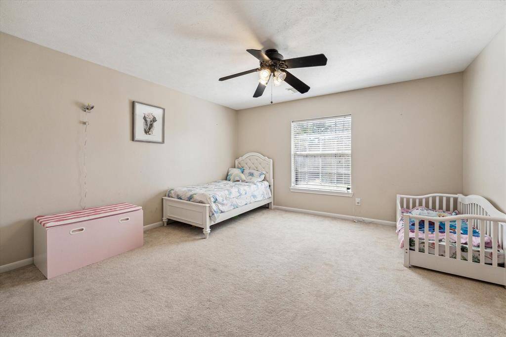 Bedroom three of the five large upstairs bedrooms on the right of the home overlooking the front yard and features carpeting, a large closet, and ceiling fan.