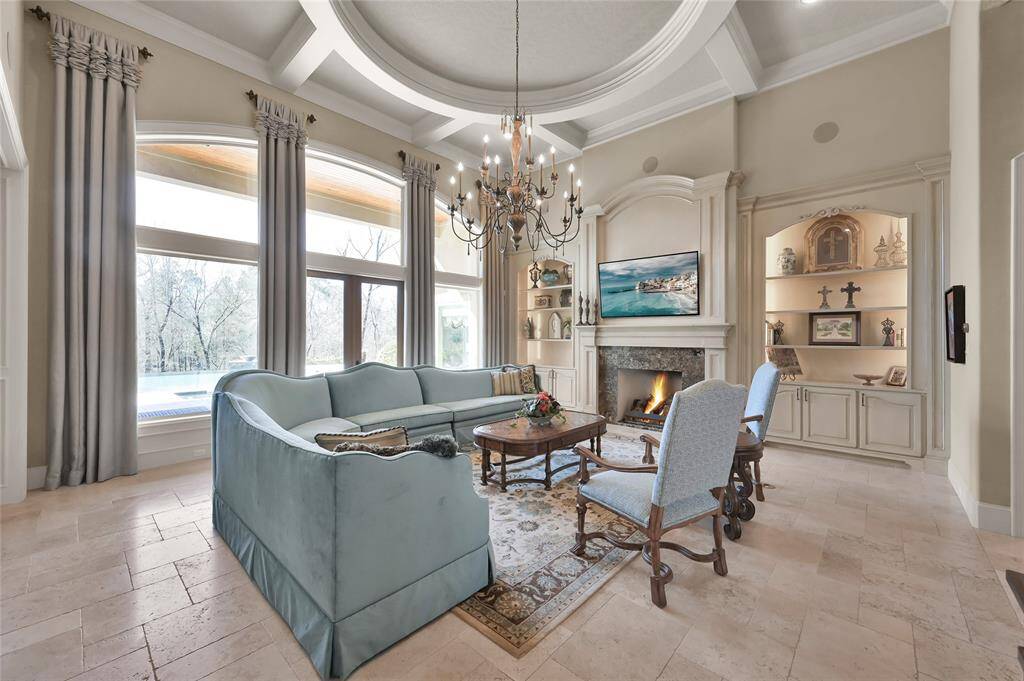 Bathed in natural light, the living room features travertine flooring, decorative ceilings, gas-log fireplace, built in cabinets and sweeping backyard views.