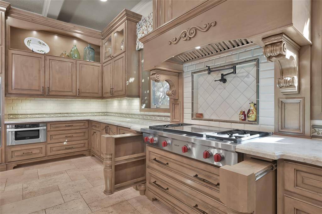 Wolf appliances including a 4-burner cooktop with center griddle, double ovens, warming drawer, pot filler and hidden spice racks make this kitchen every Chef's dream!