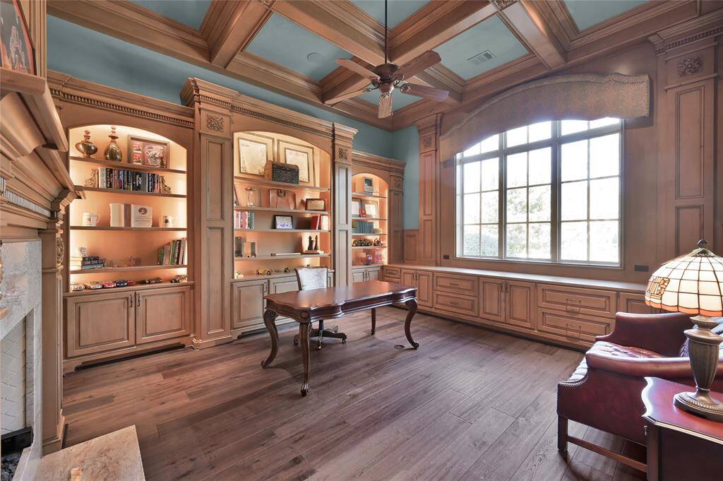 The warm study features custom wood cabinetry, coffered ceilings and a cozy gas-log fireplace.