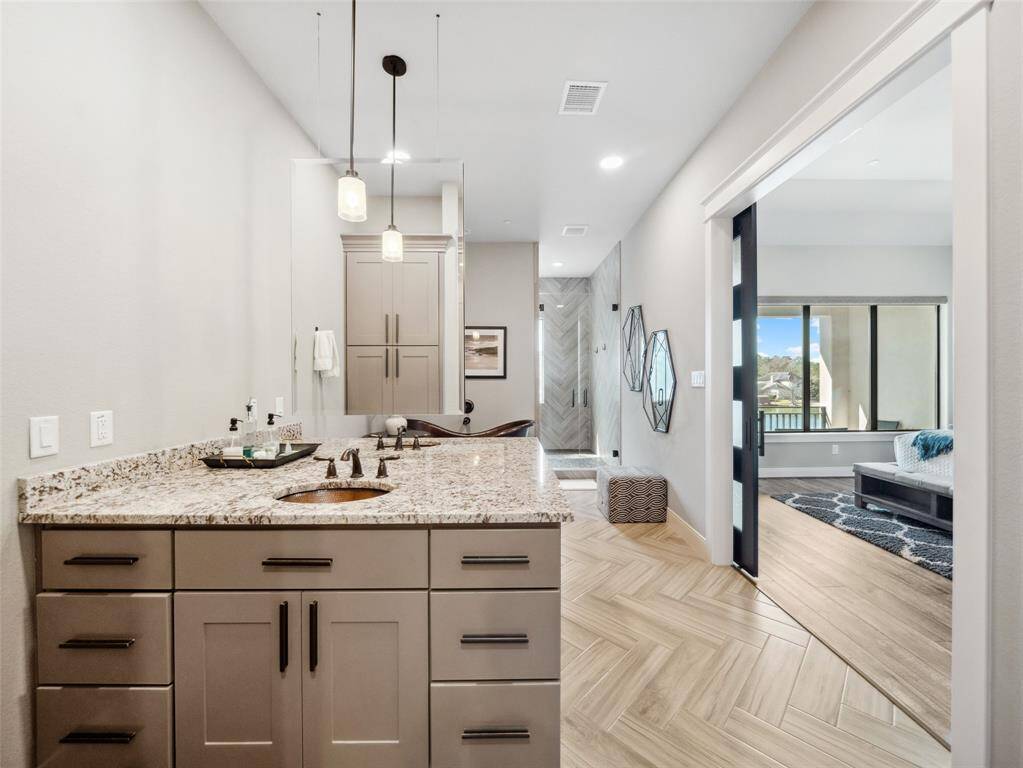 PRIMARY BATH with exquisite design selections: floating mirror separates the sink vanities, modern sliding (barn) doors close off the room, large herringbotne tile, copper sinks & deep soaking tub plus phenomenally sized shower.