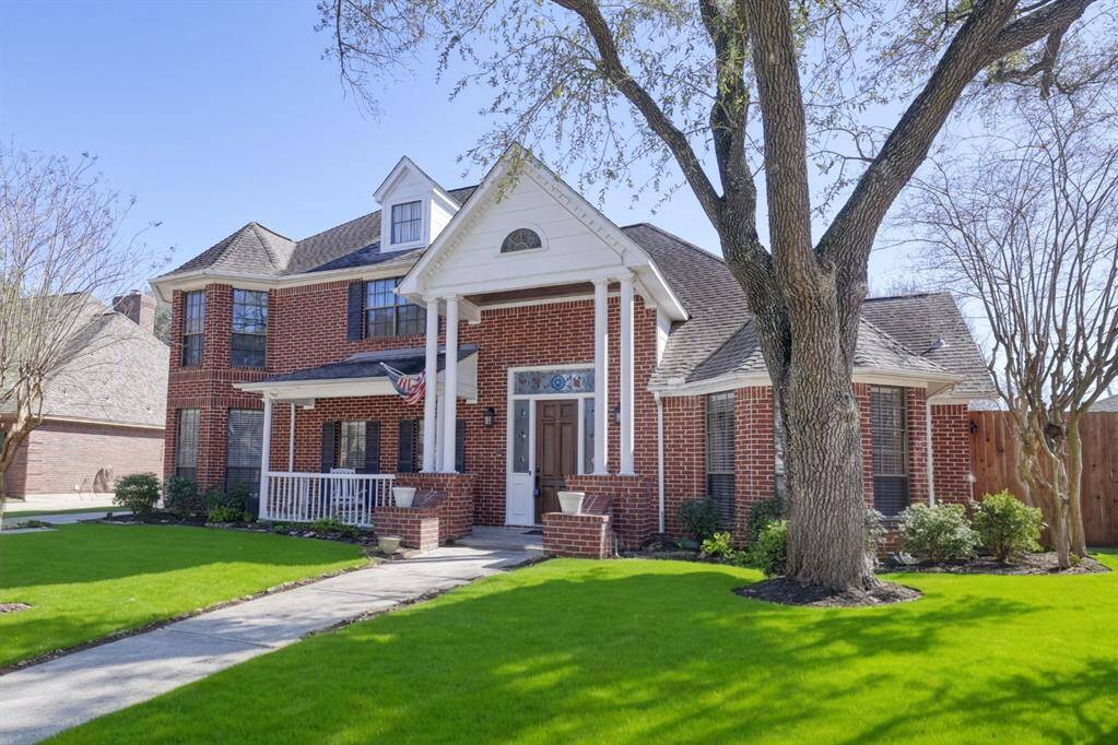 This charming two-story brick home features a welcoming front porch, mature trees, and a well-maintained lawn. Its classic design includes large windows and a gabled roof, enhancing its curb appeal. Perfect for family living in a serene neighborhood.