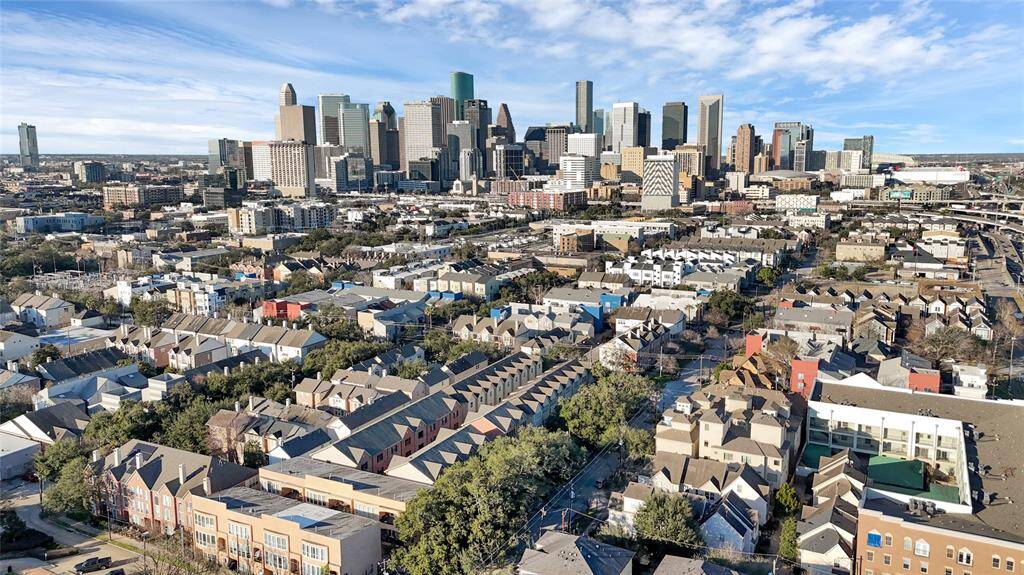 This photo showcases a vibrant urban neighborhood with a mix of townhouses and apartments. The skyline of a bustling city is visible in the background, offering a blend of residential charm and urban convenience. Perfect for those seeking proximity to city amenities.