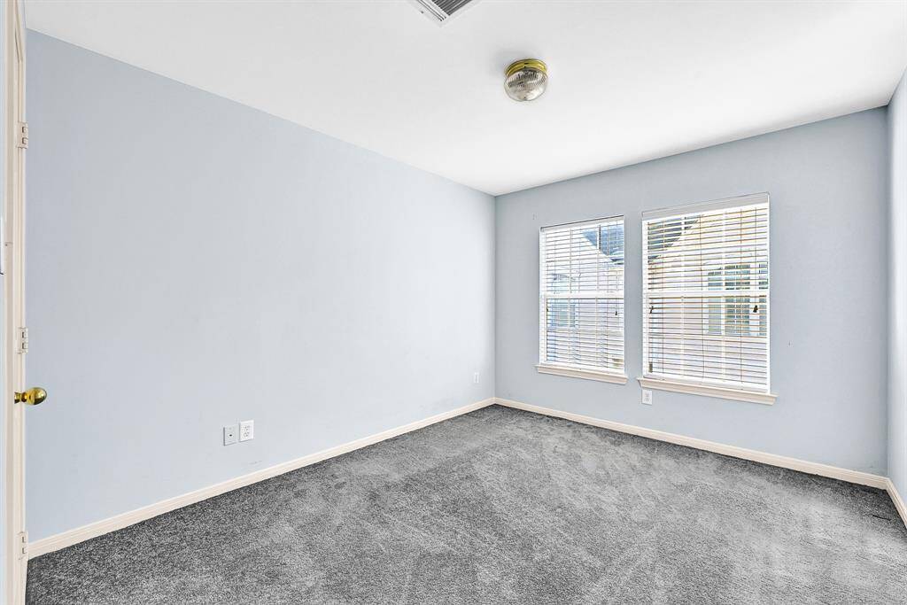 Cozy bedroom with ample natural light, perfect for guests or a home office.