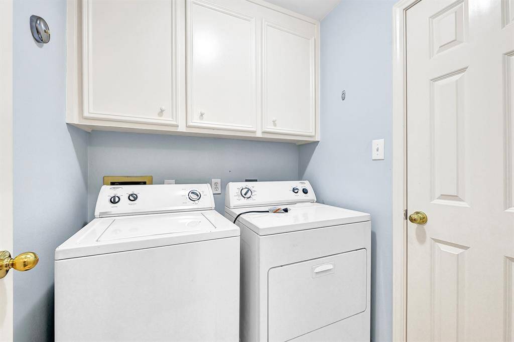 Efficient laundry room with modern washer and dryer, ample storage, and bright lighting.