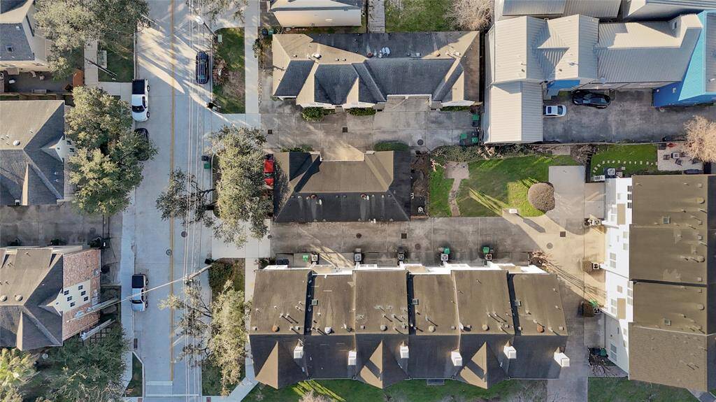 This aerial photo showcases a neighborhood with closely spaced homes and shared driveways. The area features a mix of residential buildings, with some green spaces and trees along the streets, offering a suburban feel.