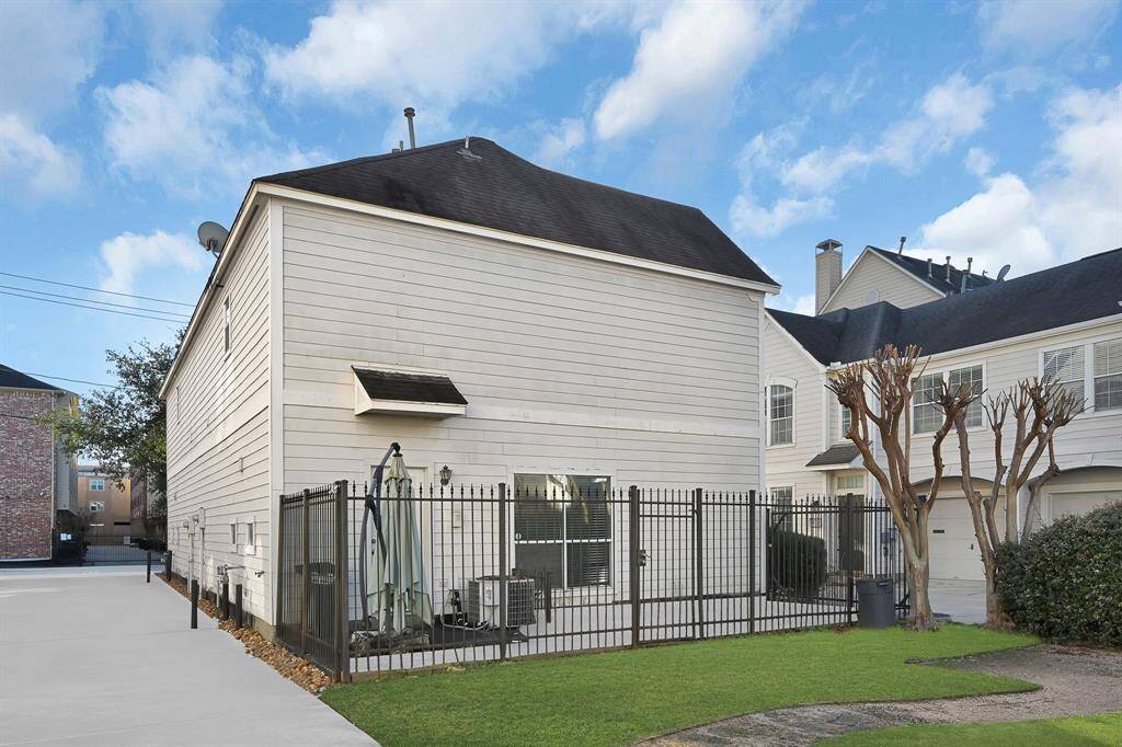 This two-story home features a clean exterior with light siding and a dark roof. It includes a small fenced yard with minimal landscaping, providing a low-maintenance outdoor space. The area appears quiet and suburban, ideal for privacy.