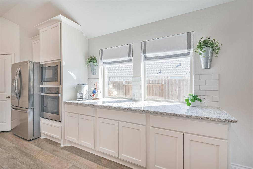 Granite counters and subway tile backsplash extend along the dining room wall, with its custom shades and natural light.