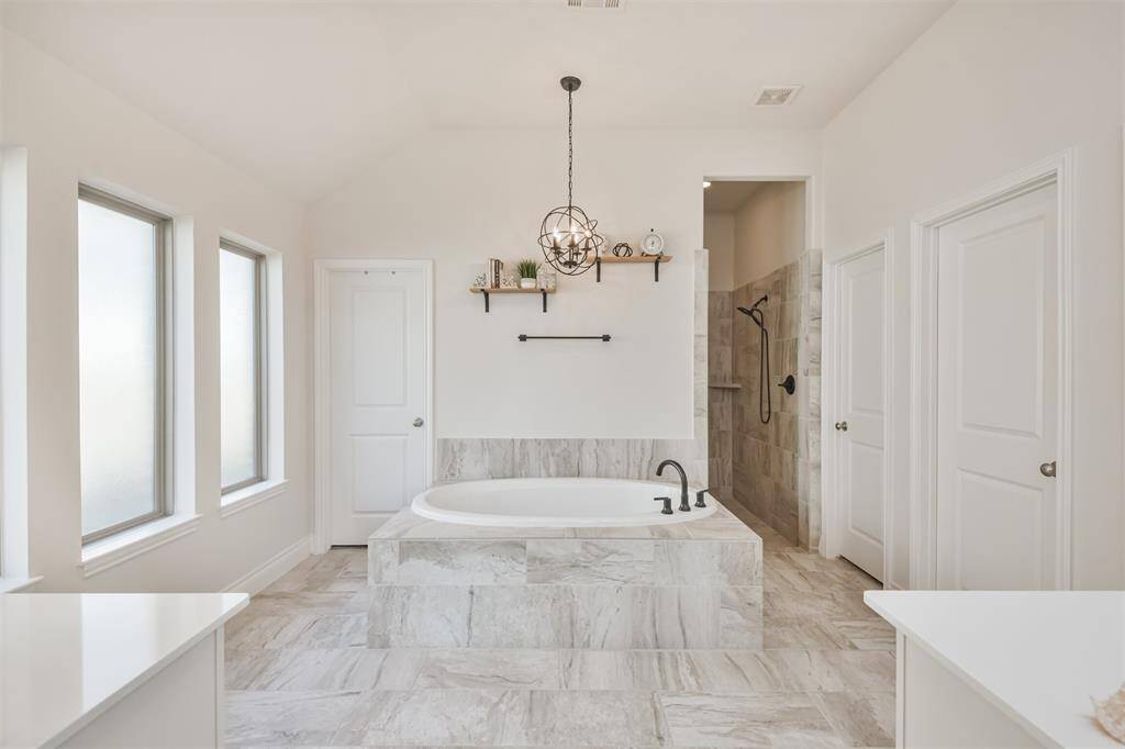 With its tile surround, wall of windows, and chandelier, this large soaking tub is the perfect spot for relaxing.