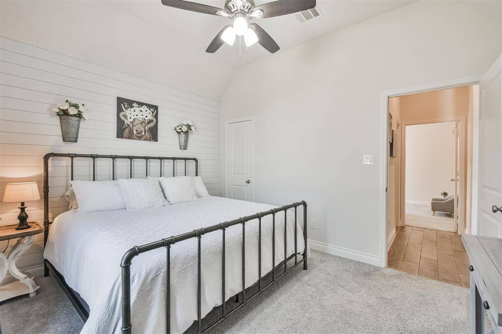Front bedroom with shiplap accent wall, ceiling fan, and walk-in closet