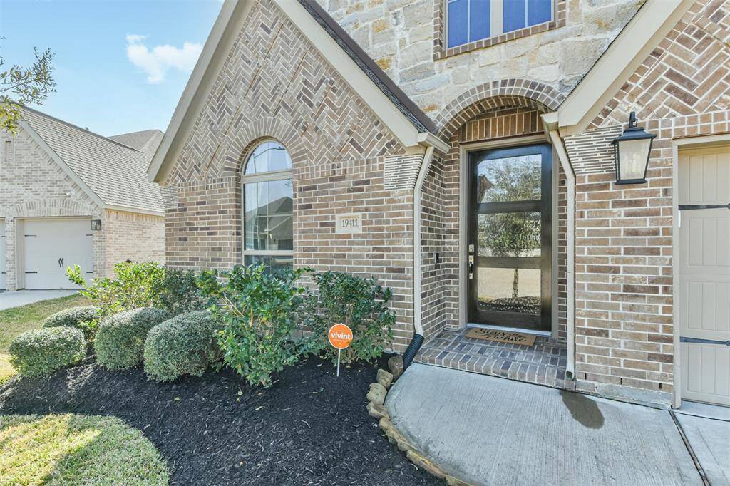 Mature landscaping, bricked front porch, and gorgeous wood and glass front door add curb appeal to this lovely home.