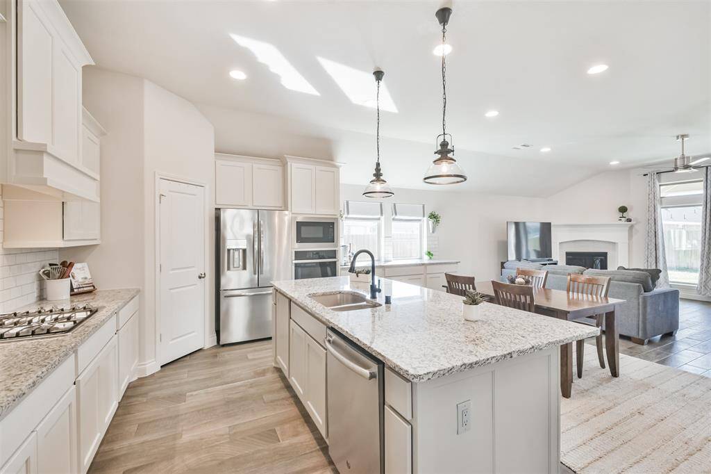 Kitchen island has cabinet wrap around with storage on both sides, breakfast bar, pendant lights, and granite counters.