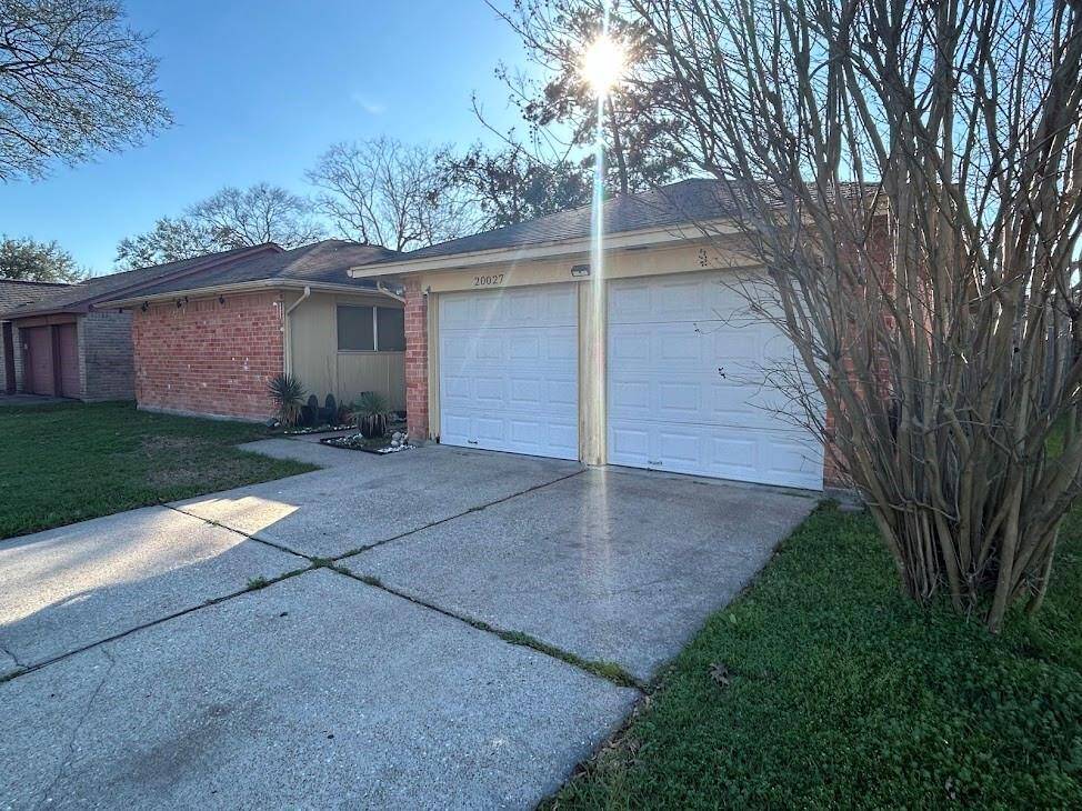 Charming single-story brick home with a two-car garage and a spacious driveway. The front yard is well-maintained, featuring mature trees and a small garden area.