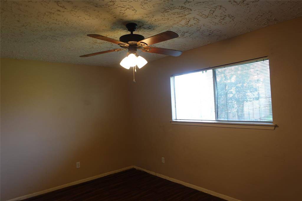 Cozy third bedroom featuring natural light and a ceiling fan, perfect for comfort and relaxation; perfect view of the backyard.