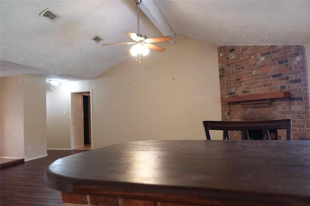 Spacious living area featuring a cozy brick fireplace and vaulted ceiling, perfect for relaxation and entertaining.