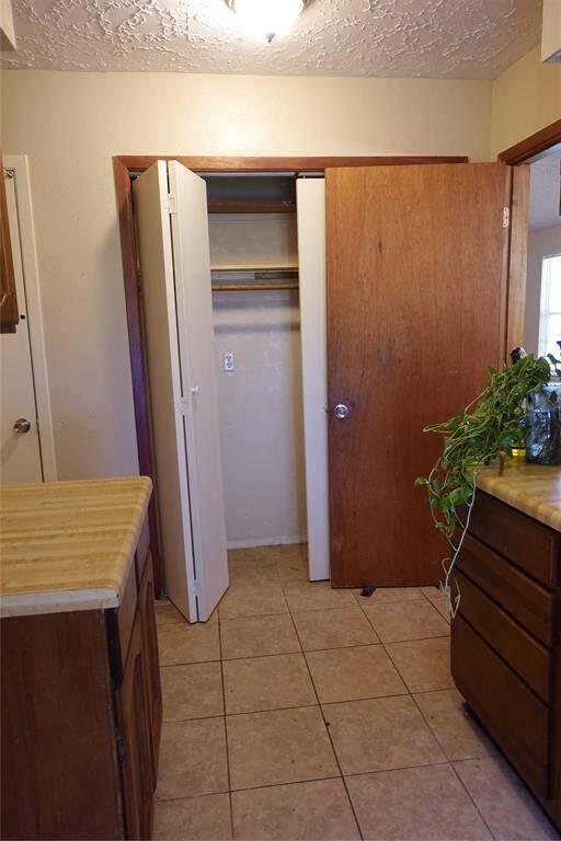 Laundry room with ample closet space, featuring tiled floors and convenient cabinetry for storage and organization.
