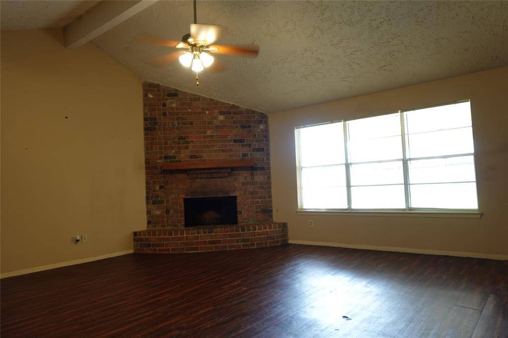 Bright living area with a cozy brick fireplace and expansive backyard views.