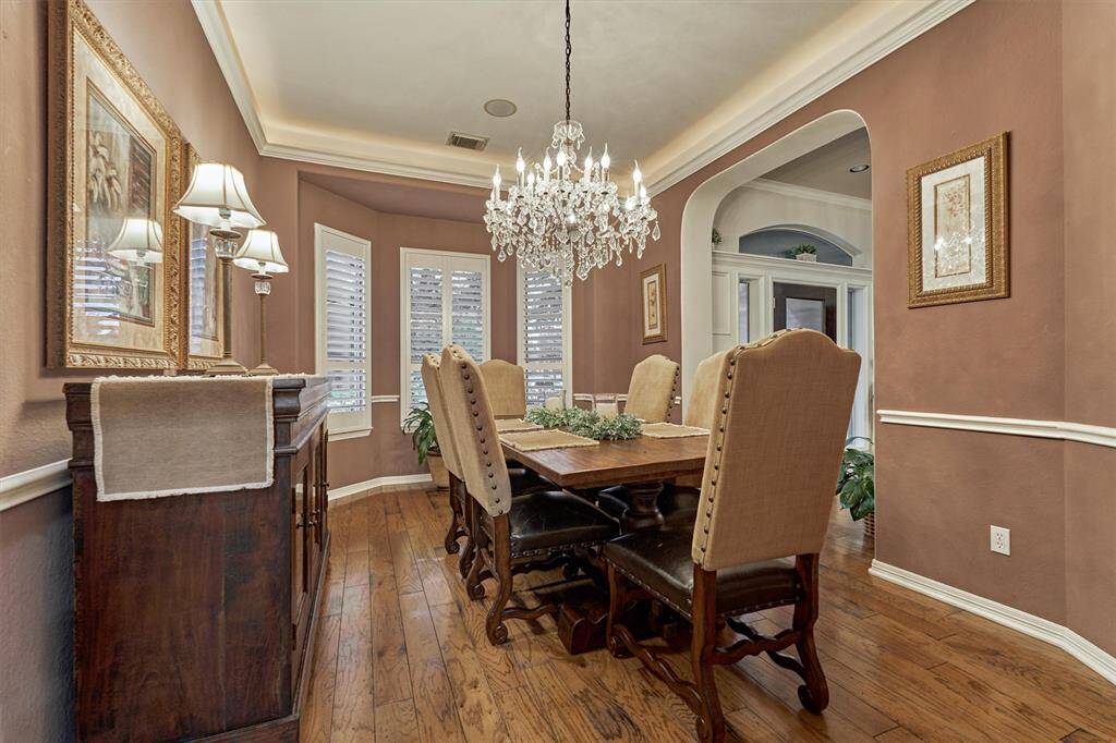 Formal dining with curved entryway and custom wood shutters.