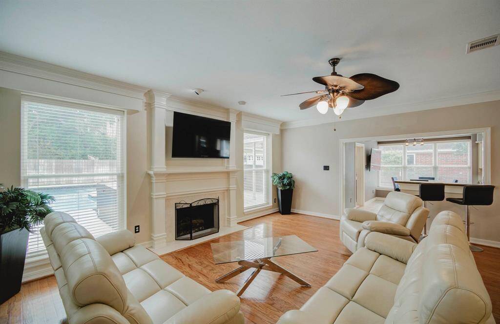 This living room offers views of the backyard and pool. The open layout connects seamlessly to a breakfast bar and kitchen area, perfect for entertaining.