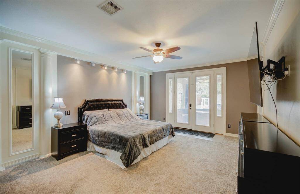 Primary bedroom with elegant French doors opening to a serene backyard retreat.