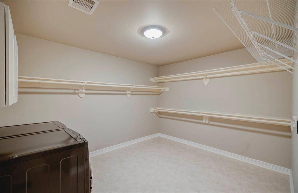 Spacious laundry room with ample shelving for storage, and neutral wall color. Ideal laundry room for organizing all of your laundry tasks.