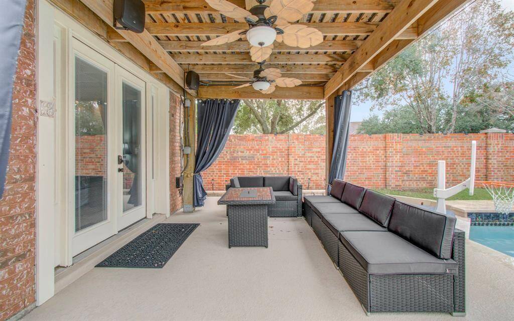 This inviting outdoor patio features a covered seating area with ceiling fans, and curtains for privacy. It overlooks your fabulous pool, providing a perfect spot for relaxation and entertaining.