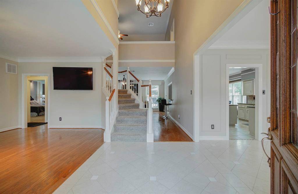 Elegant entryway with high ceilings and tile flooring leads to a cozy living area featuring hardwood floors, perfect for entertaining.
