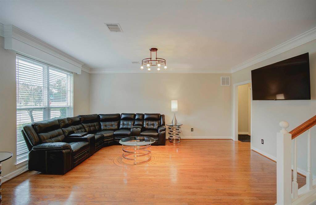 Bright and spacious living room with hardwood floors, perfect for all your furniture, offering charm and warmth.