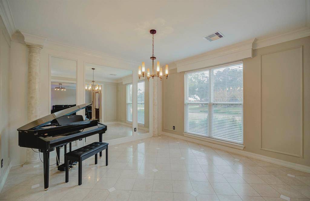 Bright and elegant formal living room with large windows, tile flooring, and stylish lighting.