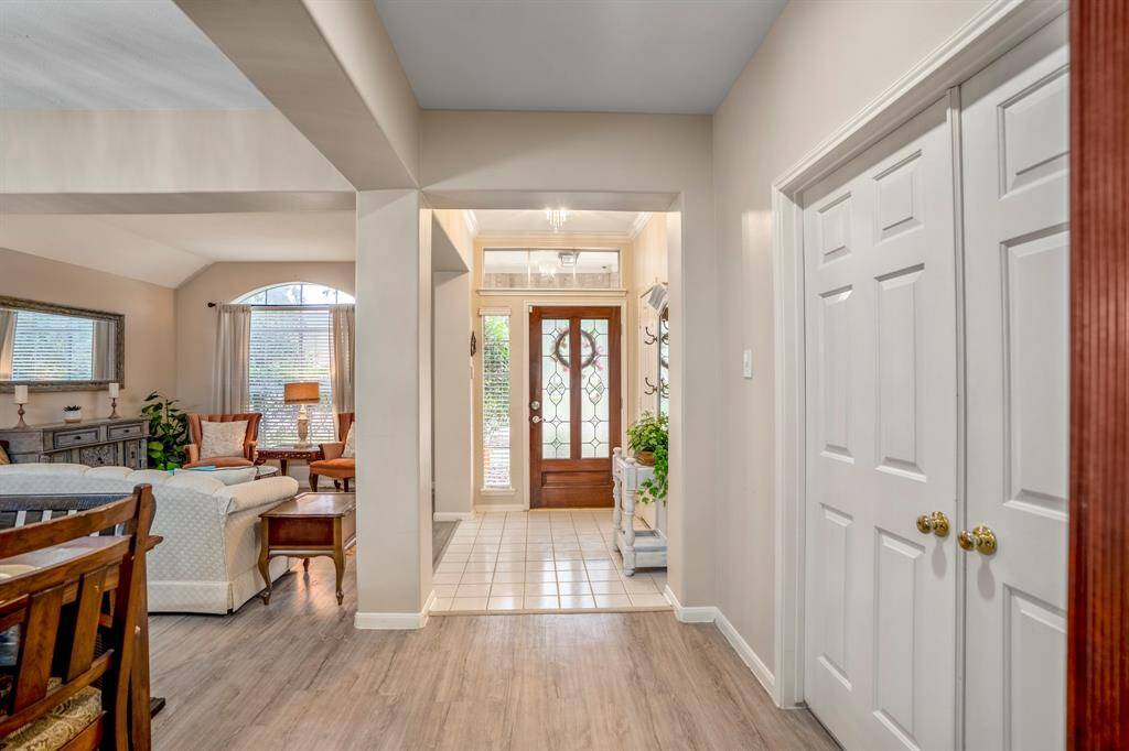 Stepping back into the entry hallway, the formal dining and living areas are on the left. Directly ahead is the front door, while to the immediate right, double doors open to the private home office, offering a quiet space for work or study.