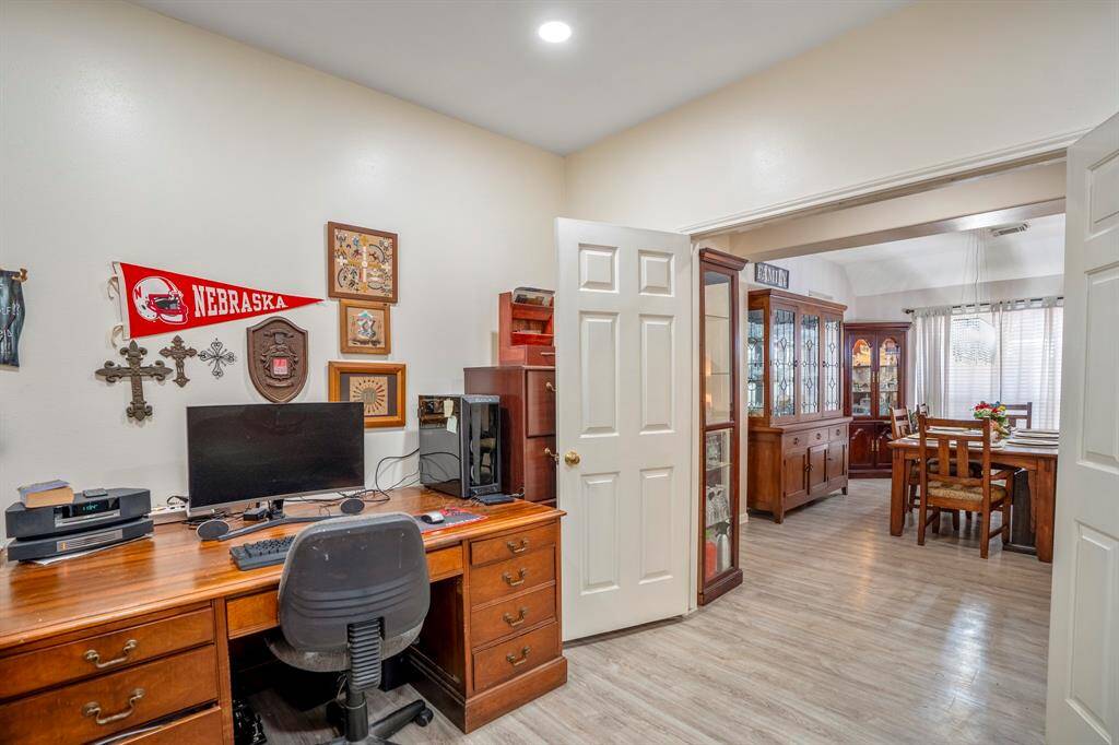 A view inside the home office, featuring a peaceful and private workspace. Through the double doors, you can see the formal dining area across the hallway, creating a connected and open flow.