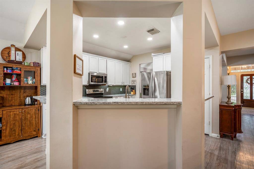 A view of the kitchen from across the island, showcasing the spacious layout with ample counter space, cabinetry, and a seamless flow into the adjoining living areas.