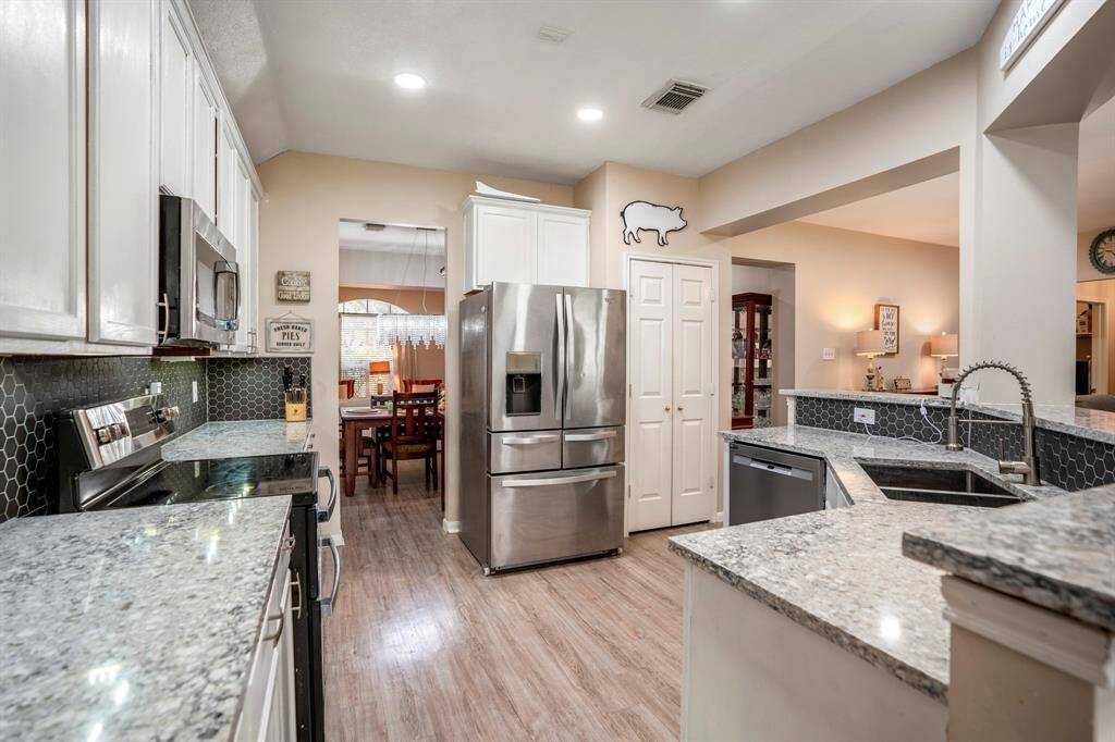 Standing near the opening to the breakfast room, looking back into the kitchen, you can see the opening to the formal dining space to the left of the fridge, with the pantry conveniently located to the right, offering easy access to both spaces.