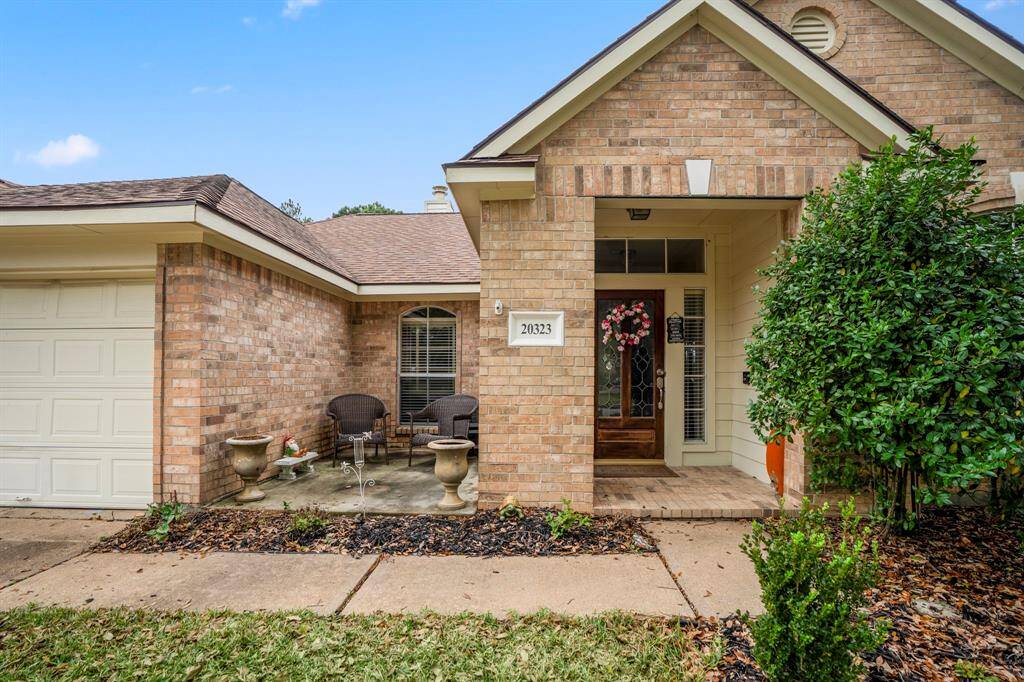 A cozy view of the front porch, featuring a charming sitting area to the left of the front door—perfect for relaxing and enjoying the peaceful neighborhood setting.