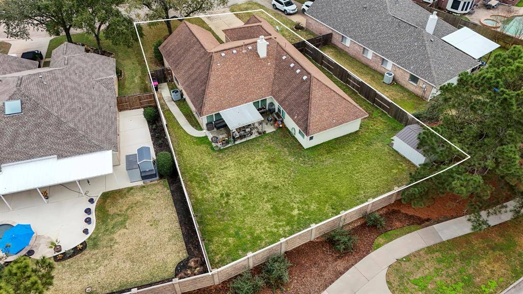 An aerial view showcasing the spacious backyard with no rear neighbors, offering privacy and a peaceful setting. The covered patio is visible, providing the perfect spot for outdoor relaxation and entertaining.