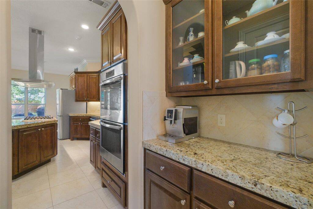 This beautifully designed butler’s pantry seamlessly connects to the gourmet kitchen, offering the perfect blend of style and functionality. Featuring rich custom cabinetry with glass-paneled uppers, sleek granite countertops, and a stylish tile backsplash, this space provides ample storage and a convenient prep area.Perfect for entertaining, the butler’s pantry enhances the flow between the kitchen and dining areas, making hosting effortless.