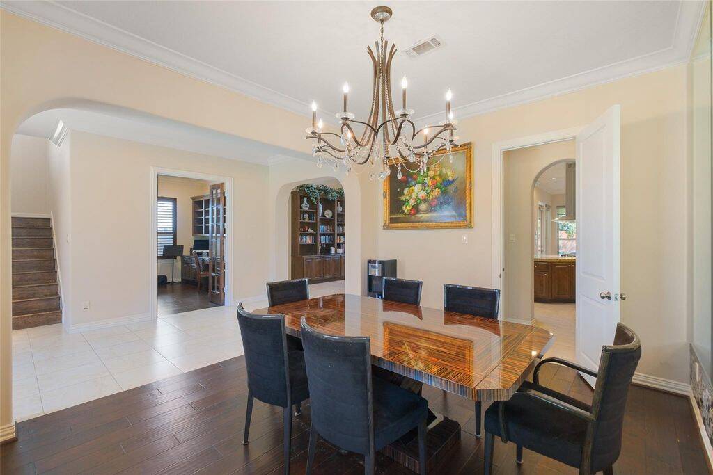 Dine in sophistication in this stunning formal dining room, where elegance meets warmth. A dazzling crystal chandelier casts a radiant glow over the space, enhancing the ambiance for intimate dinners or grand gatherings. The rich hardwood floors provide a refined contrast to the light-filled room, while the mirrored accent wall adds depth and a touch of glamour.