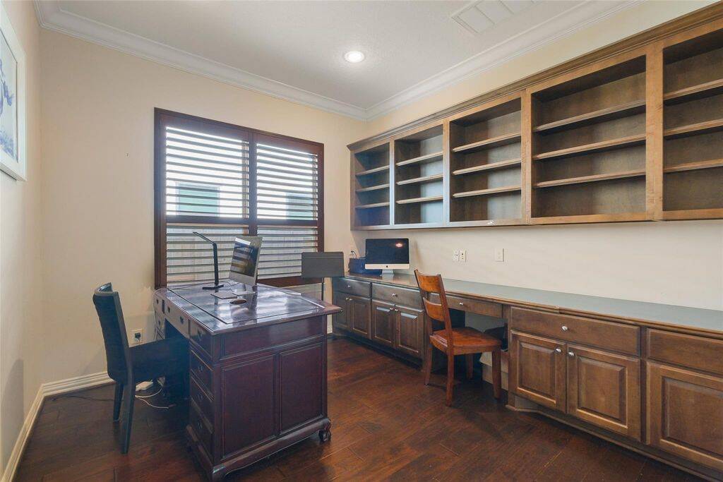 Elevate your productivity in this stunning home office, designed for both efficiency and style. Featuring rich wood built-in shelving and cabinetry, this space offers ample storage and display options, keeping your work area organized and clutter-free.