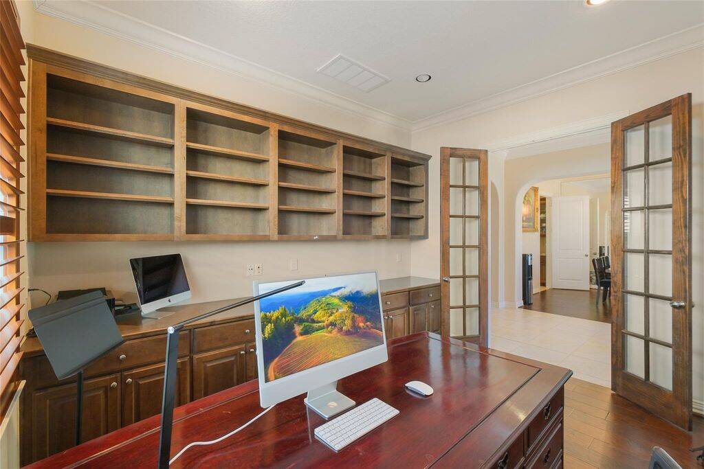 Natural light filters through the large window with elegant wooden shutters, creating a bright yet private ambiance. The rich hardwood floors and crown molding add warmth and sophistication, enhancing the overall appeal of the room.Whether you need a quiet retreat for work or a stylish study space, this home office is the perfect blend of functionality and elegance. Make it yours today!