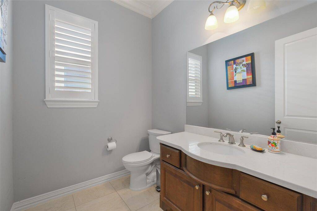 Adjacent to the office, this beautifully designed half bath offers a perfect blend of sophistication and functionality. Light gray walls provide a soft, modern touch, while the sleek white countertop and warm wooden vanity add a timeless charm. Natural light pours in through two shuttered windows, enhancing the space’s bright and airy ambiance. Thoughtfully designed with both style and convenience in mind, this half bath is ideal for guests and everyday use. Elevate your home with this elegant powder room!