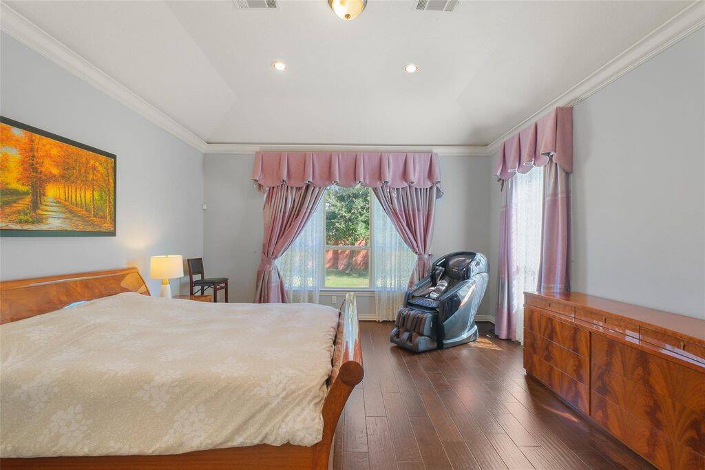 Retreat to this elegant primary suite, where comfort and style come together effortlessly. The rich hardwood floors and soft gray walls create a tranquil atmosphere, complemented by crown molding and recessed lighting for a touch of sophistication.