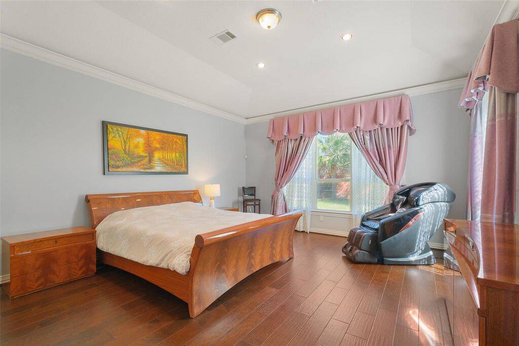 Expansive windows framed by classic drapery invite natural light while offering serene views of the lush backyard. The spacious layout easily accommodates a king-sized bed, seating area, or additional furnishings for a truly personalized retreat.