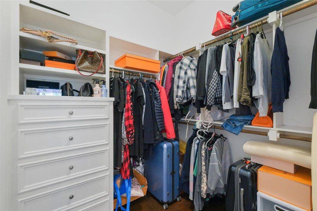 Spacious walk-in closet with ample shelving and hanging space, featuring built-in drawers and organized compartments for storage.